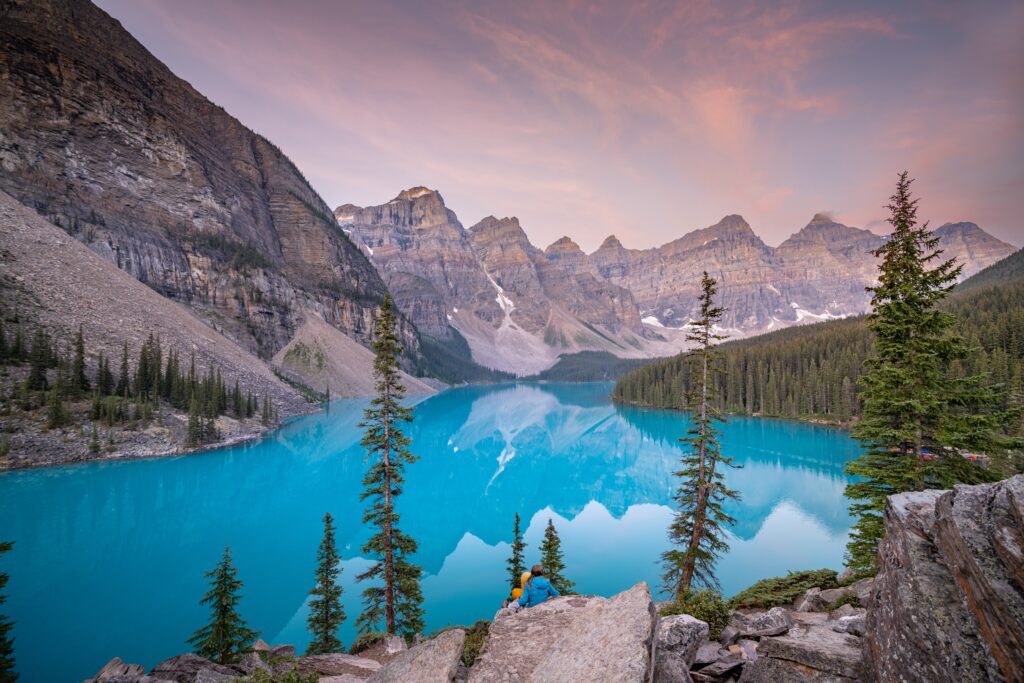 Een koppel geniet van de zonsondergang met een roze gloed in Lake Moraine in het Canadese Banff National Park tijdens een reis door West-Canada