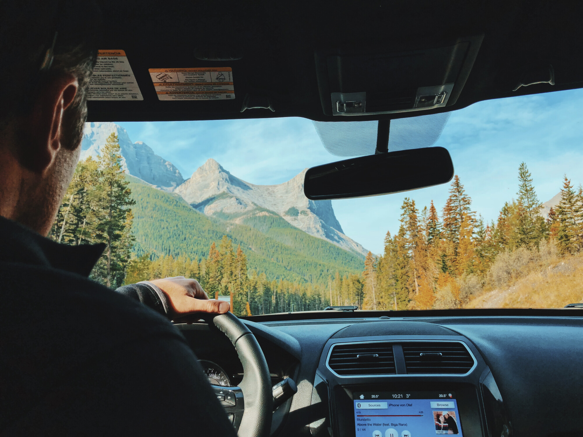 Een man rijdt een huurauto tijdens zijn rondreis door de Rocky Mountains in Canada